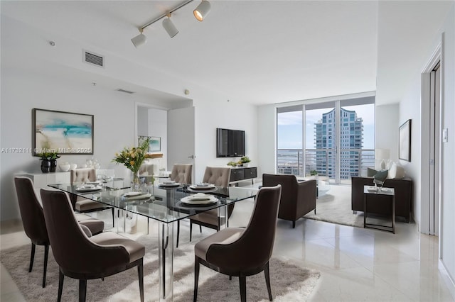 dining area featuring light tile patterned floors, rail lighting, and floor to ceiling windows