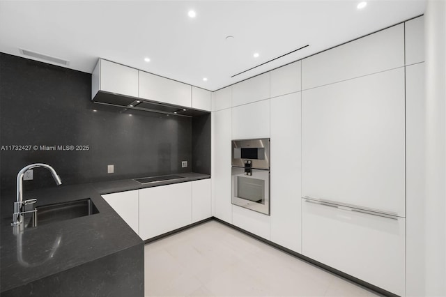 kitchen featuring modern cabinets, a sink, black electric cooktop, white cabinetry, and backsplash