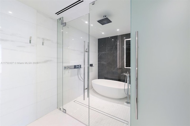 bathroom with a stall shower, tile walls, a freestanding bath, and tile patterned floors