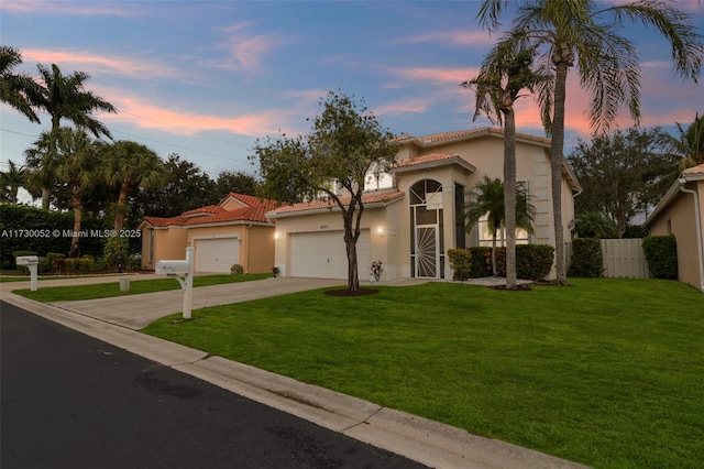 mediterranean / spanish home with a garage and a lawn