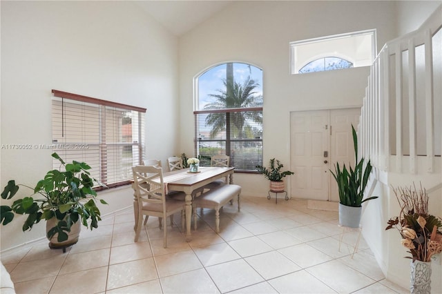 dining space featuring light tile patterned floors and high vaulted ceiling