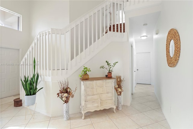 stairs with tile patterned floors and a high ceiling