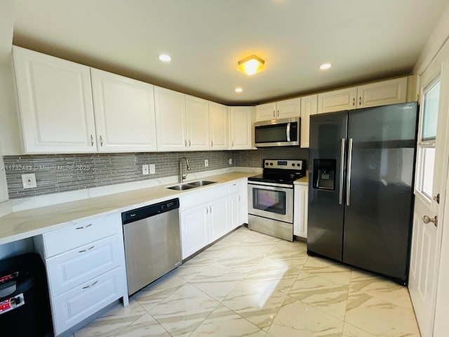 kitchen with light stone countertops, appliances with stainless steel finishes, sink, and white cabinets