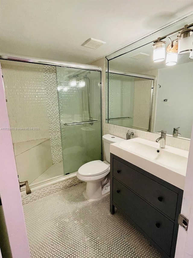 bathroom featuring a shower with door, vanity, and toilet