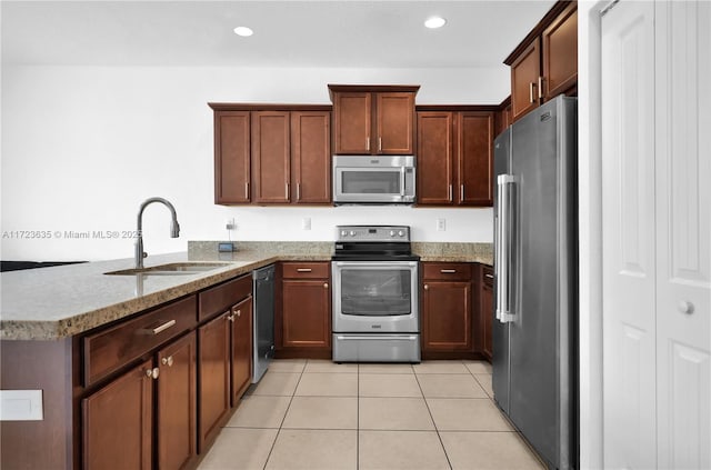 kitchen with sink, light tile patterned floors, stainless steel appliances, light stone counters, and kitchen peninsula