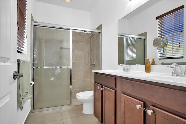 bathroom featuring a shower with door, vanity, tile patterned floors, and toilet