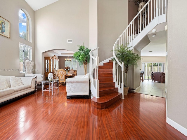 interior space with an inviting chandelier, hardwood / wood-style floors, and a towering ceiling