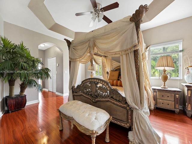 bedroom with hardwood / wood-style flooring, ceiling fan, and a raised ceiling