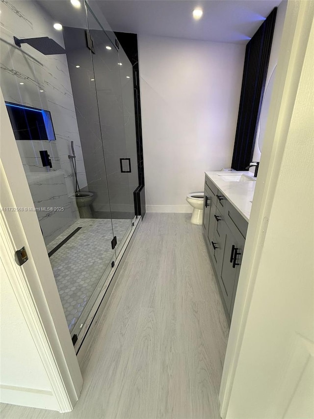 bathroom with vanity, a shower with shower door, wood-type flooring, and toilet