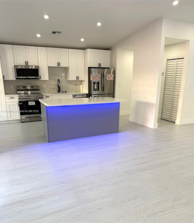 kitchen with stainless steel appliances, white cabinetry, and a kitchen island