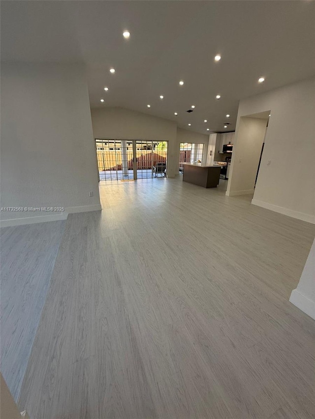 unfurnished living room featuring vaulted ceiling and light wood-type flooring