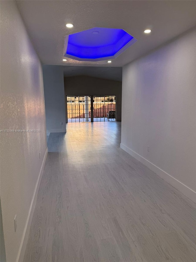 hallway with hardwood / wood-style flooring and a raised ceiling