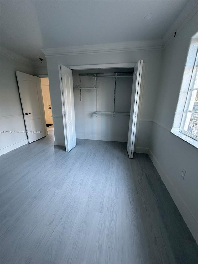 unfurnished bedroom with crown molding, hardwood / wood-style floors, and a closet