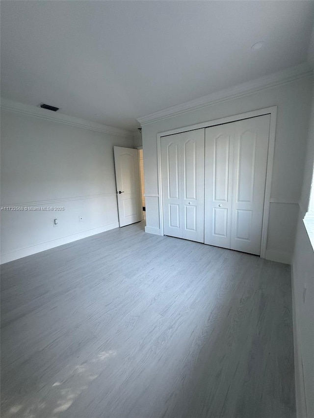 unfurnished bedroom with ornamental molding, hardwood / wood-style floors, and a closet