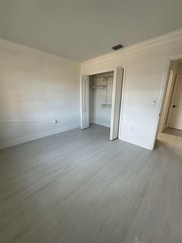 unfurnished bedroom with ornamental molding, a closet, and light wood-type flooring