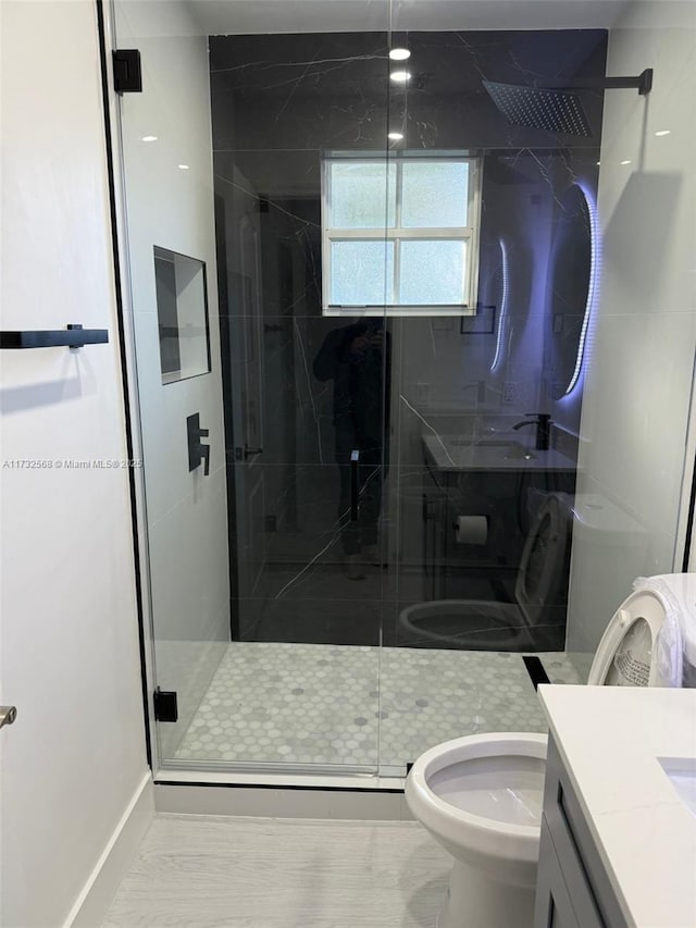 bathroom featuring vanity, toilet, and a shower with shower door