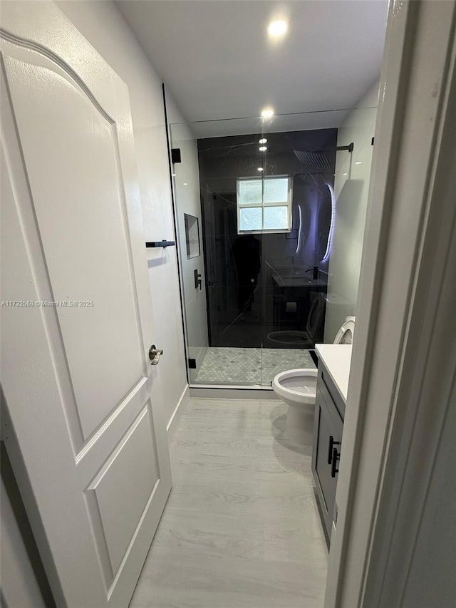 bathroom with a shower with door, vanity, and toilet