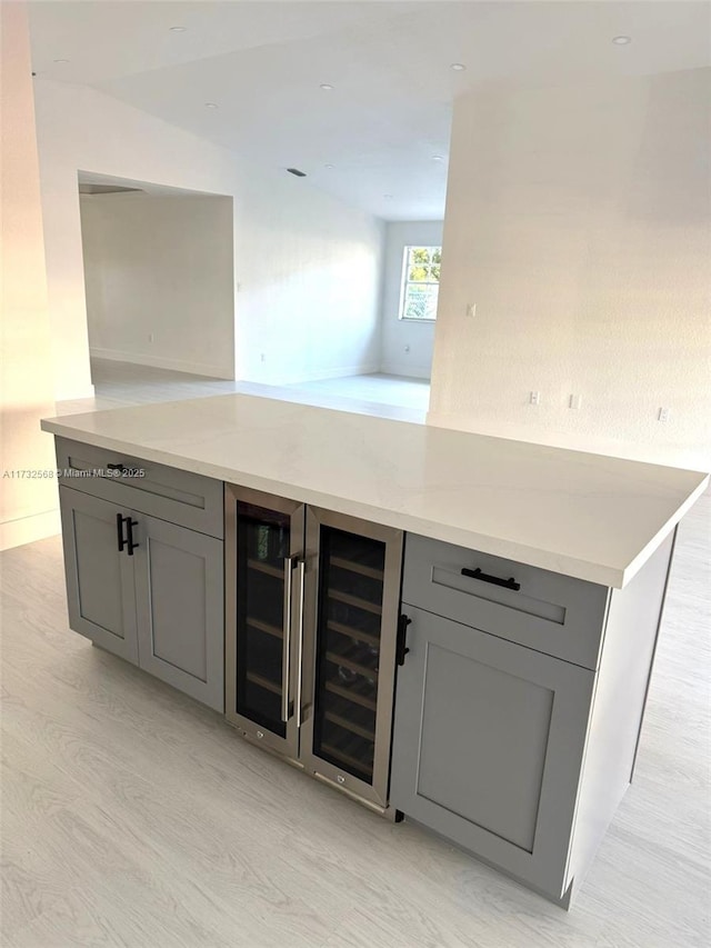 bar featuring gray cabinetry, light hardwood / wood-style flooring, and beverage cooler