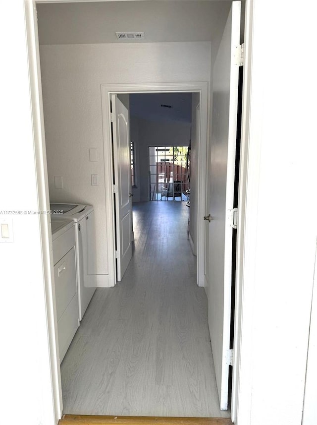 corridor with independent washer and dryer and light wood-type flooring