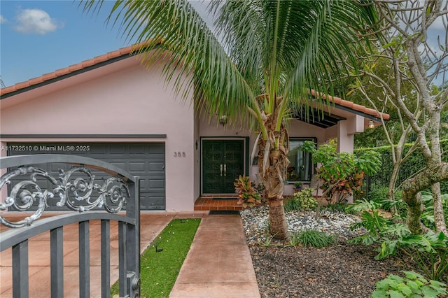 view of exterior entry featuring a garage and stucco siding