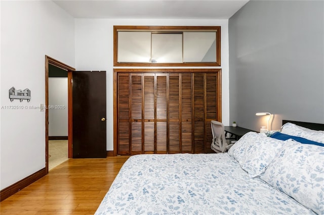 bedroom with a closet, light wood-style flooring, and baseboards