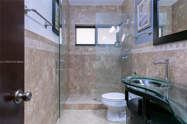 bathroom with tile walls, toilet, a stall shower, vanity, and tile patterned floors