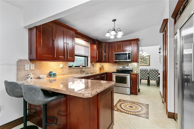 kitchen with pendant lighting, appliances with stainless steel finishes, glass insert cabinets, a sink, and a peninsula