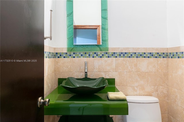 half bathroom with toilet, tile walls, and a sink