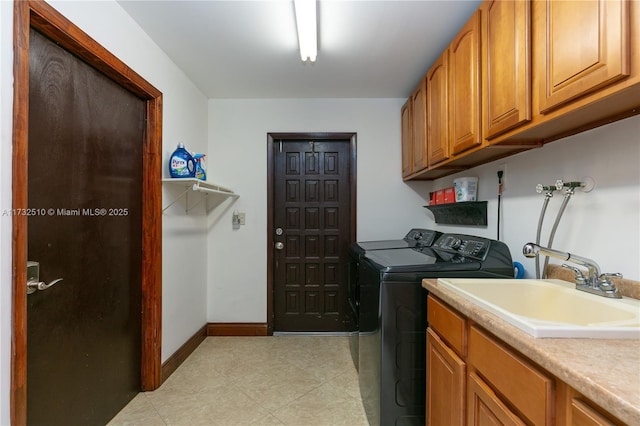 laundry room featuring washer and clothes dryer, a sink, cabinet space, and baseboards