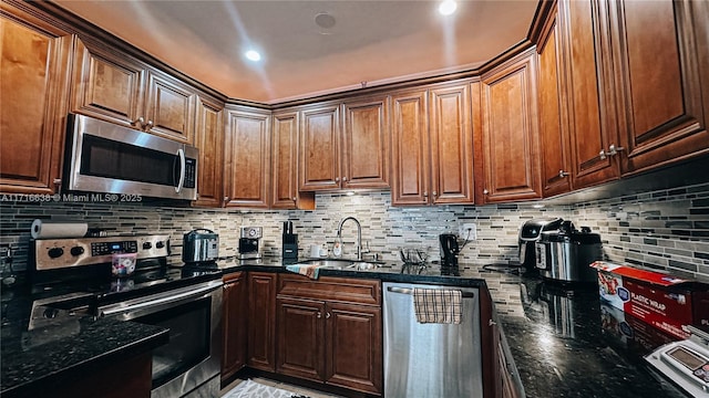 kitchen featuring sink, backsplash, dark stone counters, and appliances with stainless steel finishes