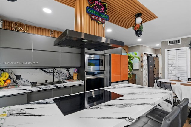 kitchen with gray cabinets, a breakfast bar area, stainless steel appliances, light stone counters, and island exhaust hood