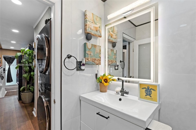 bathroom featuring stacked washer / dryer, vanity, and hardwood / wood-style flooring