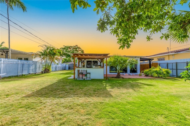 back house at dusk featuring a yard and a pergola