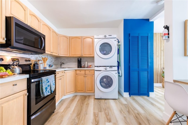 clothes washing area featuring sink, stacked washing maching and dryer, and light hardwood / wood-style floors