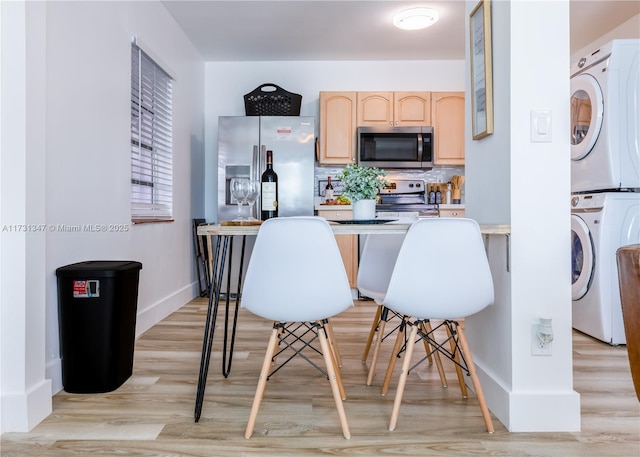 kitchen featuring stacked washer and dryer, appliances with stainless steel finishes, tasteful backsplash, light hardwood / wood-style floors, and light brown cabinets