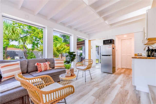 sunroom / solarium featuring beamed ceiling and sink