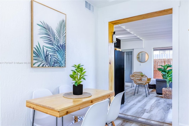 dining space featuring beamed ceiling and hardwood / wood-style flooring