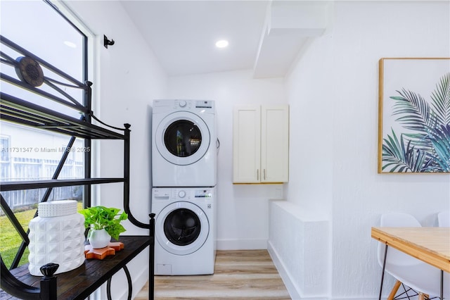 clothes washing area with stacked washing maching and dryer and light wood-type flooring