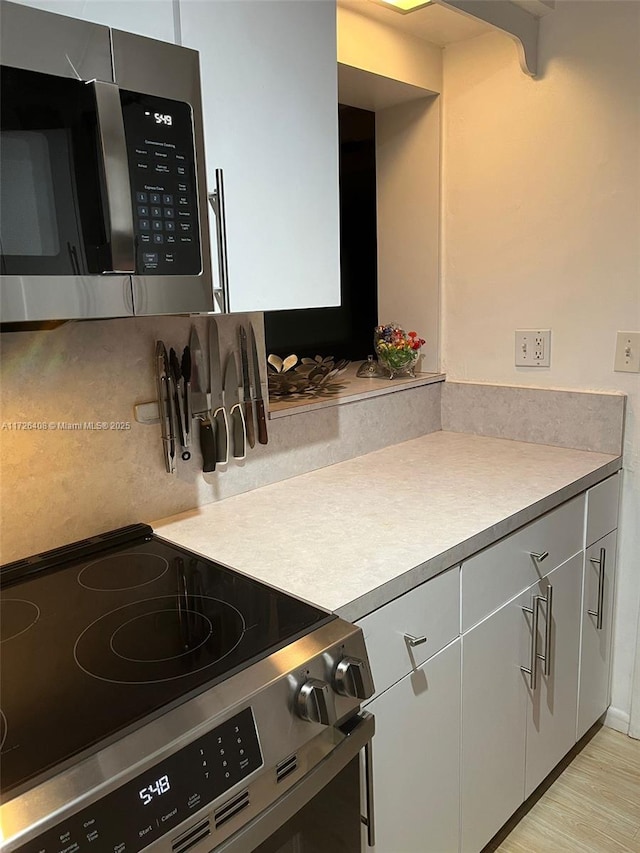 kitchen featuring stainless steel appliances, light hardwood / wood-style floors, and decorative backsplash