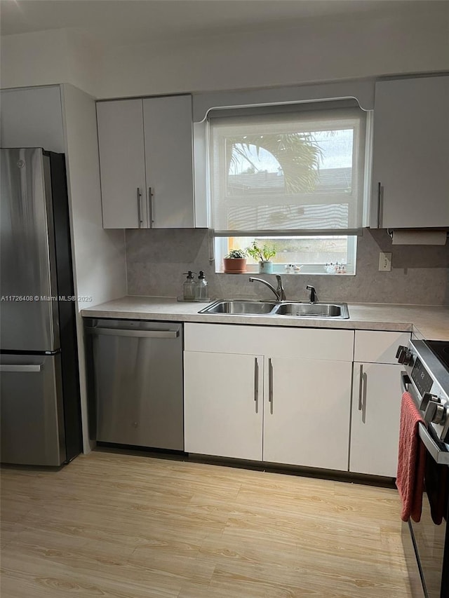 kitchen featuring stainless steel appliances, sink, white cabinets, and light hardwood / wood-style floors