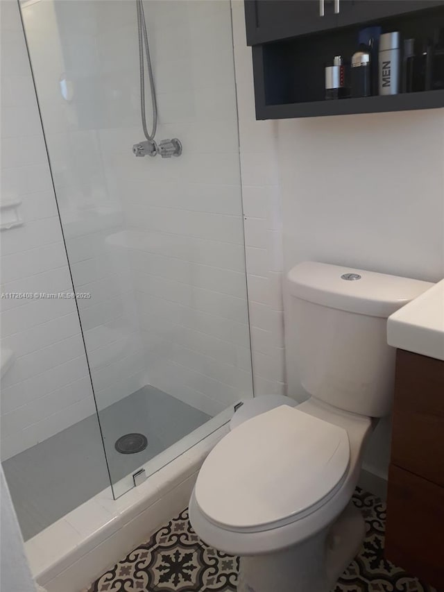 bathroom featuring vanity, toilet, and a tile shower