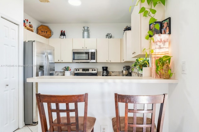 kitchen with stainless steel appliances, a breakfast bar, sink, and kitchen peninsula