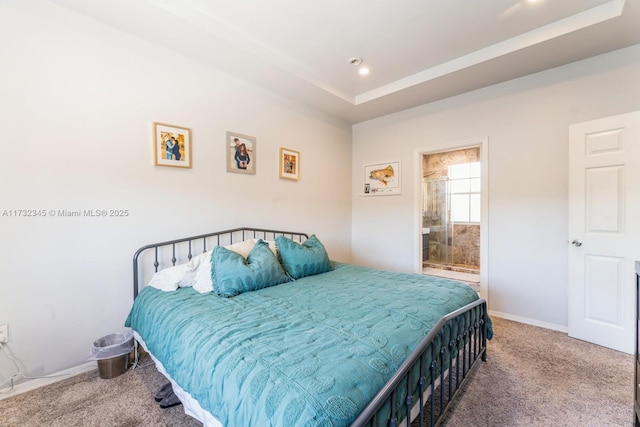 carpeted bedroom featuring ensuite bathroom and a tray ceiling