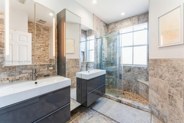 bathroom featuring walk in shower, vanity, and tile walls