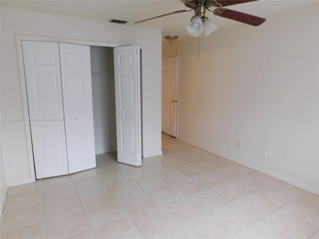 unfurnished bedroom with light tile patterned flooring, ceiling fan, and a closet