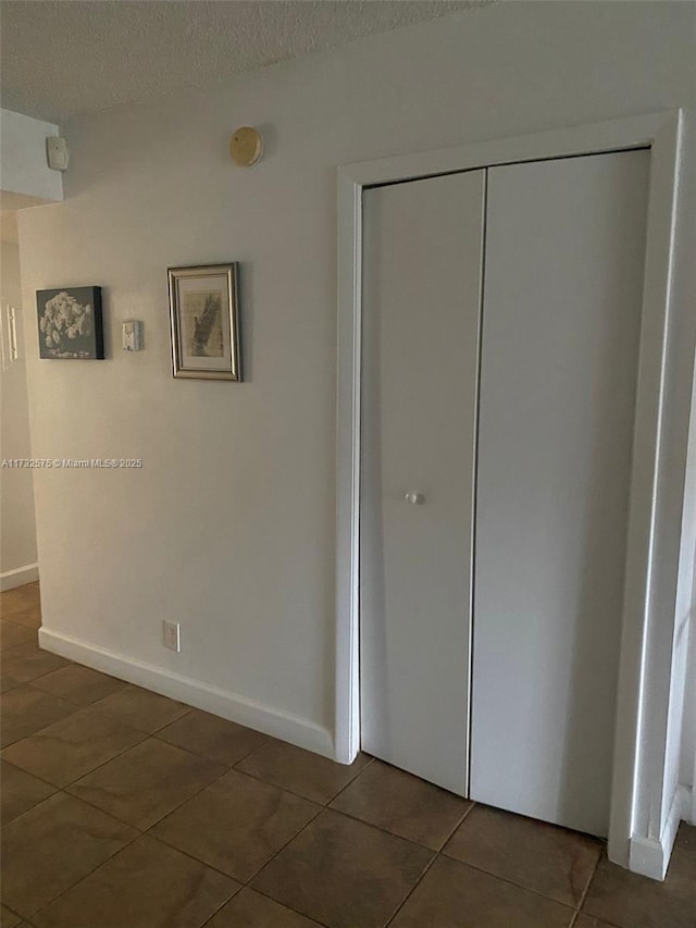 unfurnished bedroom featuring a textured ceiling, a closet, and dark tile patterned floors