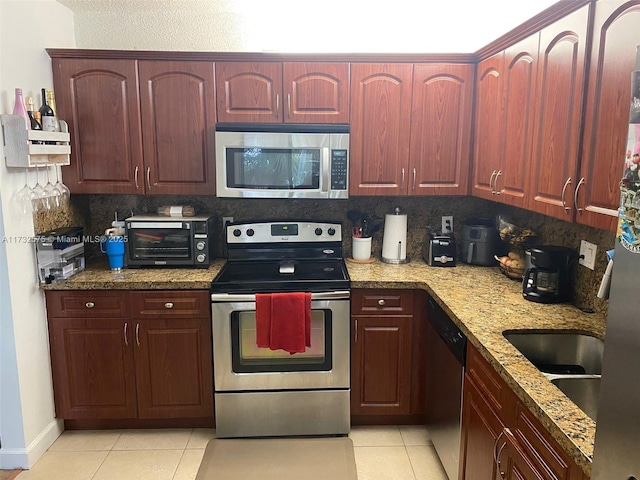 kitchen with sink, appliances with stainless steel finishes, tasteful backsplash, light stone countertops, and light tile patterned flooring