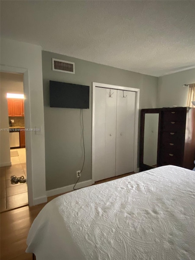 bedroom with a textured ceiling, a closet, and light hardwood / wood-style flooring