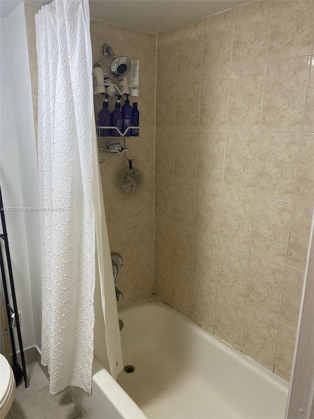 bathroom with toilet, tile patterned floors, and shower / bath combo with shower curtain