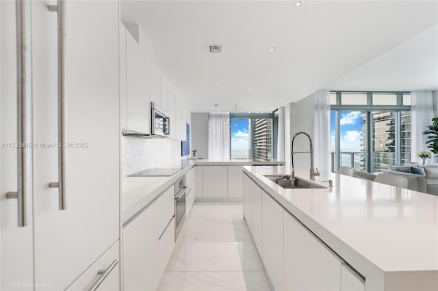 kitchen with appliances with stainless steel finishes, sink, a center island with sink, and white cabinets